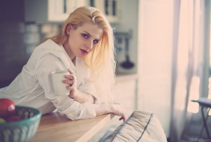 stunning portrait of the blonde girl Takha with a cup of tea and a white shirt in the kitchen